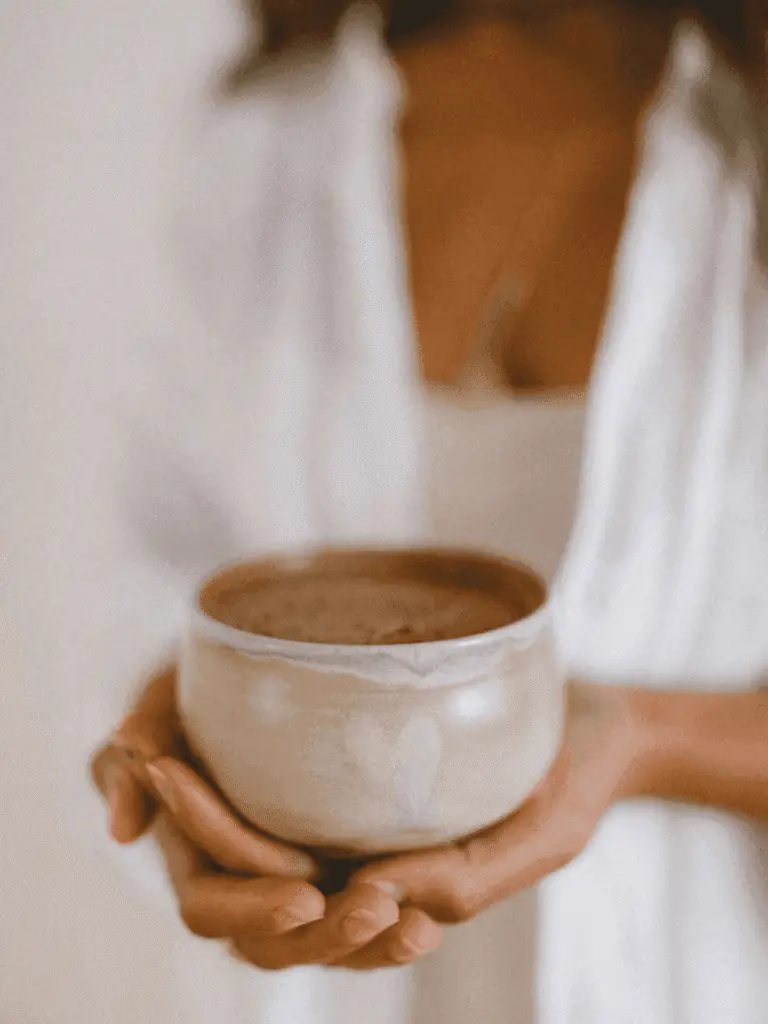 Vrouw houdt kom met ceremoniële cacao vast cacao ceremonie thuis