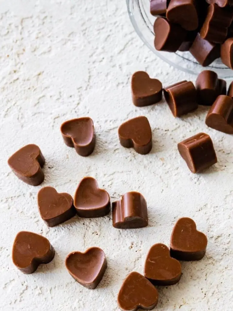 Mini Choco Bliss hartjes verspreid naast glazen pot ceremoniële cacao voor microdoseren met plantmedicijn