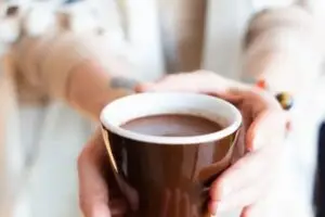 Vrouw die een kopje ceremoniële cacao vasthoudt als symbool voor warmte, ritueel en hartopening