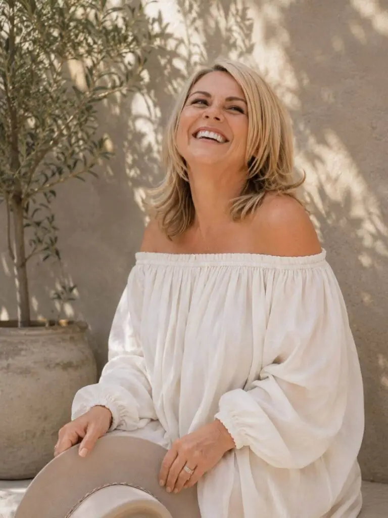 Vrouw lacht ontspannen buiten in witte off-shoulder blouse – Helen Adriana, oprichter Healing Heart