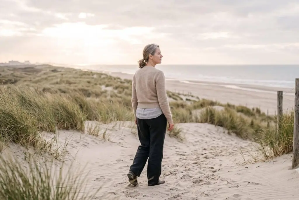 Vrouw wandelt bij zonsondergang door de duinen, symbool voor loskomen van traumabonding en herstel
